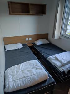 deux lits assis dans une pièce avec une fenêtre dans l'établissement DOMA Mobil home 3 chambres Litteau, à Litteau