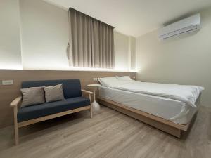 a bedroom with a bed and a blue chair at Jian Guo Hotel in Pingtung City