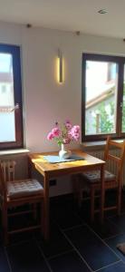 a table with flowers on it with two windows at M-Suites Petit - Near Frankfurt Airport in Hattersheim