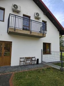 a white house with a balcony and two chairs at Dom Weselny Izabela Noclegi in Osiek