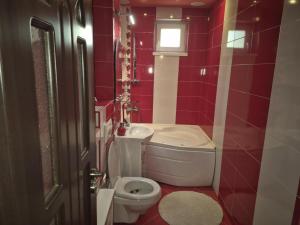 a red bathroom with a toilet and a sink at Tranzit apartman 3 in Odorheiu Secuiesc
