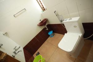 a bathroom with a white toilet and brown tiles at Smiley Homestay in Varkala +15 photos