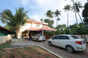 two cars parked in a parking lot in front of a house at Smiley Homestay in Varkala
