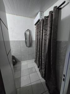 a bathroom with a shower with curtains and a mirror at Aluguel de quarto por diária in São Luís