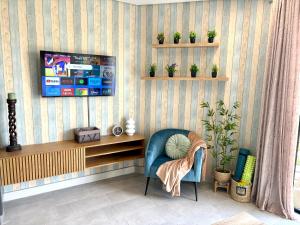 a living room with a blue chair and a tv at Table View Escape in Cape Town