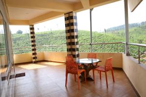 a balcony with a table and chairs and a view at HAPPY NEST home stay valparai in Vālpārai