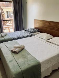 zwei Betten in einem Hotelzimmer mit Handtüchern darauf in der Unterkunft Apto 2 quartos - Condomínio Frente Mar in Beberibe