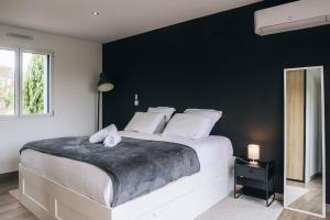 a bedroom with a large bed with a black wall at La Villa Marais in Déols
