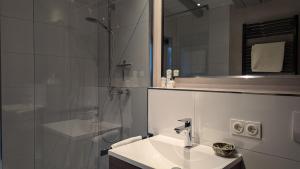 ein weißes Badezimmer mit Waschbecken und Dusche in der Unterkunft Ferienhaus mit großer Terasse in Kellenhusen + 8 Fotos