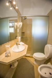 Un baño con lavabo, inodoro y espejo. en Joan Miró Hotel, en Punta del Este
