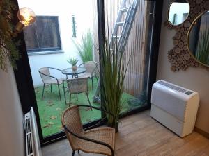 eine Terrasse mit einem Tisch, Stühlen, einem Tisch und einem Fenster in der Unterkunft Thermo'Spa - Gîte Spa Privatif in Calais