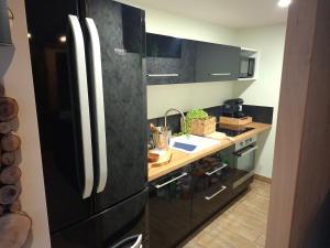 eine Küche mit einem schwarzen Kühlschrank und einer Spüle in der Unterkunft Thermo'Spa - Gîte Spa Privatif in Calais + 8 Fotos