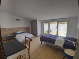 a bedroom with two beds and a table and a window at Gîte Pink House in Rainville