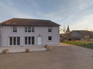 a white house with a driveway and a church at Gîte Pink House in Rainville