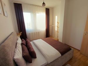 een slaapkamer met een bed met kussens en een raam bij Aria Apartment in Pristina +49 foto's