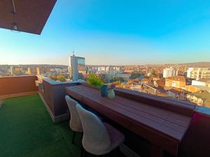 een balkon met een houten tafel en 2 stoelen bij Aria Apartment in Pristina