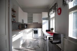 a kitchen with white cabinets and a table and chairs at Willa Wanha Apteekki in Seinäjoki