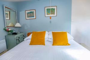 a bedroom with a bed with two yellow pillows at Wilf's Barn, romantic cottage with free parking in Wedmore