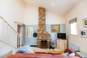 a living room with a fireplace and a couch at Wilf's Barn, romantic cottage with free parking in Wedmore