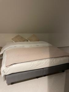 a bed with white sheets and pillows on it at De Kempische Hoef in Westerlo