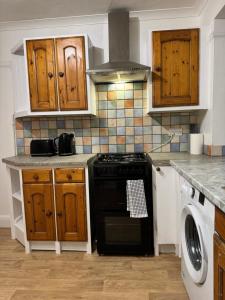 EarlswoodにあるLondon Gatwick Guest Houseのキッチン(黒いコンロ、木製キャビネット付)