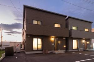 a black building with a sunset in the background at Noctis豊田 ジャグジー肩湯付お風呂75型TV 最大12名宿泊可能 in Toyota