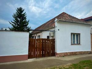 a white house with a wooden fence and a tree at Fehérlak in Tata