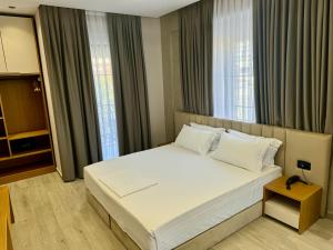 a bedroom with a large white bed with windows at Comfort Rezidence In Hotel in Tirana
