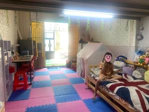 a little girl sitting on a bed in a bedroom at Homestay rất gần Gigamall Phạm Văn Đồng in Ho Chi Minh City