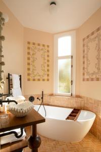 a large white tub in a bathroom with a window at Verneuil la douce in Verneuil d’Avre et d’Iton