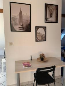 una mesa con una silla y cuadros en la pared en Duplex sous mon toit, en Altkirch