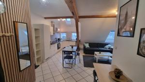 a living room and kitchen with a couch and a table at Duplex sous mon toit in Altkirch