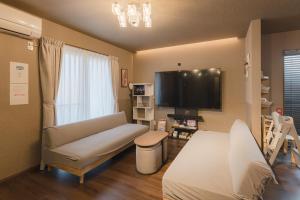 a living room with a couch and a flat screen tv at Noctis豊田 ジャグジー肩湯付お風呂75型TV 最大12名宿泊可能 in Toyota