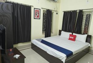 une chambre avec un lit avec un oreiller rouge dessus dans l'établissement Hotel Tara Maa Guest House, à kolkata