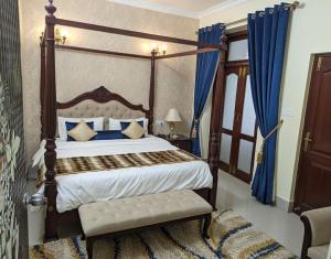 - une chambre avec un lit à baldaquin et des rideaux bleus dans l'établissement Hotel Tara Maa Guest House, à kolkata