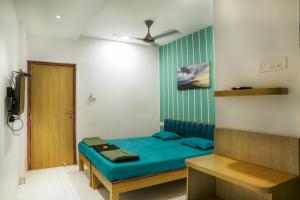 a bedroom with a bed with blue sheets and a door at Hotel Royal Usi in Dapoli