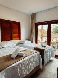 Dos camas en una habitación de hotel con ventana. en Morros da Barra chalé 05, en Barra Grande