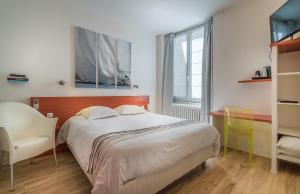 a bedroom with a bed and a chair and a window at Hotel La Marine, Vieux Port in La Rochelle