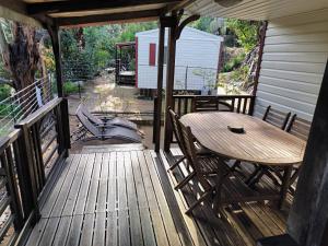 eine Holzterrasse mit einem Tisch und Stühlen darauf in der Unterkunft Mira Monti Location in Belvédère