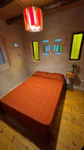 une chambre avec un lit recouvert d'une couette orange et des fenêtres dans l'établissement Tierra de Arroyo, Mallin-Tanti, à Tanti 9 autres photos