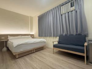 a bedroom with a bed and a blue chair at Jian Guo Hotel in Pingtung City +22 photos