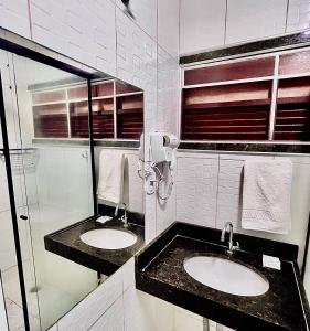 a bathroom with two sinks and a glass shower at Pousada La Riviera - Pé na areia e Passeios em Maragogi in Maragogi