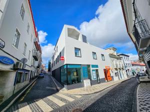 a white building on a cobblestone street at Apartamento Sonho Jardim in Ponta Delgada