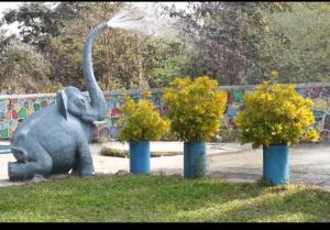 a statue of an elephant standing between two trees at Yellow House in Zirad