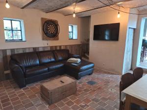 a living room with a leather couch and a tv at Vakantiehuis 6 personen-rustig en karaktervol in Geraardsbergen