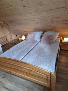 a bed in a wooden room with two pillows at Agroturystyka Cieślarówka in Lubawka