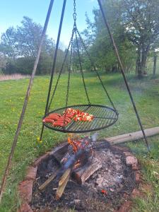 a grill with hot dogs cooking over a fire at Agroturystyka Cieślarówka in Lubawka