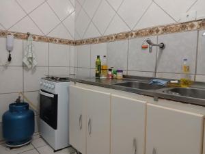 a kitchen with a sink and a stove at Quarto aconchegante na melhor localização do Recife in Recife