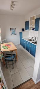 a kitchen with blue and white cabinets and a table at Ankerplatz Lichtblick in Travemünde