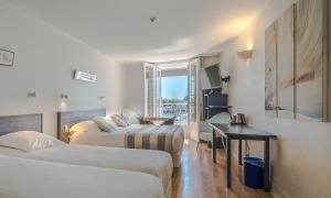 Cette chambre comprend deux lits et un bureau. dans l'établissement Hotel La Marine, Vieux Port, à La Rochelle
